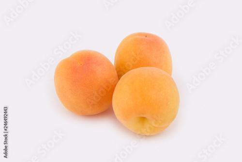 Three apricots lie side by side isolated on white background. Close-up photo