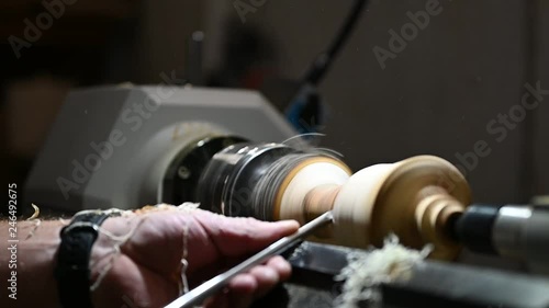 man with chisel edits wood on turnery with flying saw dust photo