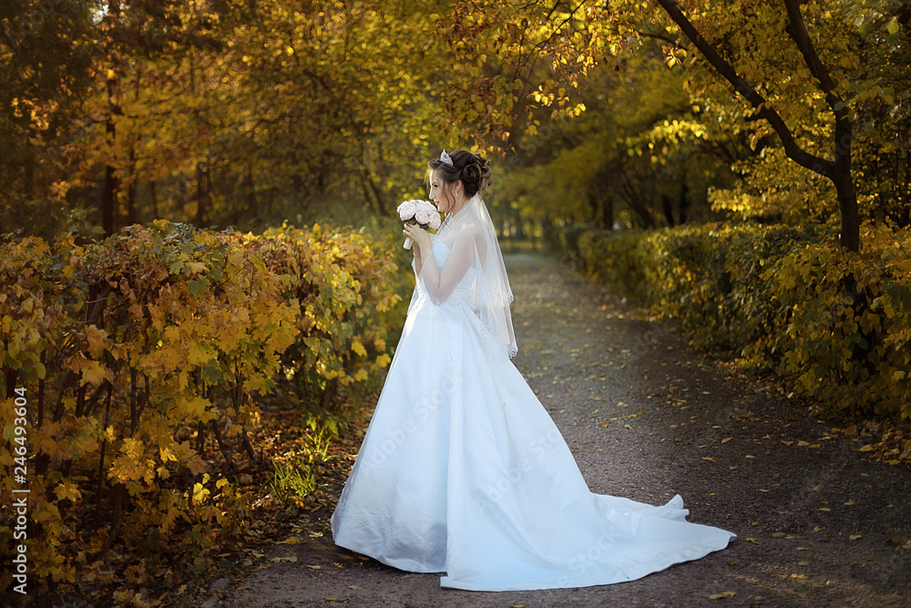 wedding. the bride stands on the path with a bouquet of roses in their hands, smelling. full height, horizontal