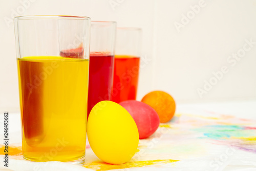 Prepearing for Easter. coloring painting eggs in glasses with color Yellow, red, orange. copyspace