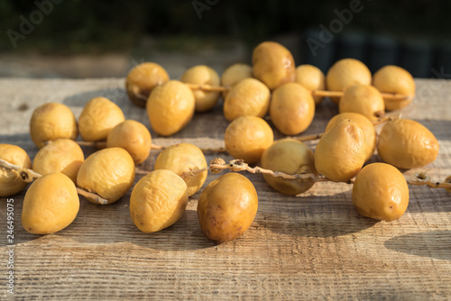 Fresh yellow dates on a sprigs on rustic wooden background. Side view