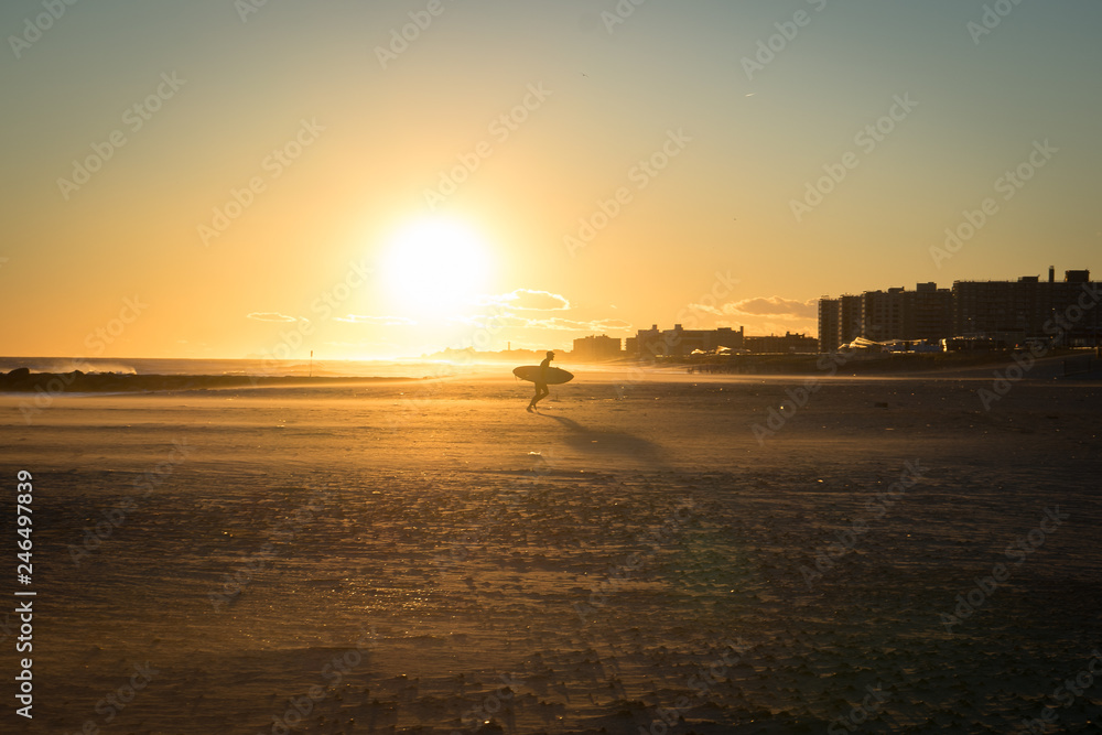 surfer on beach at sunset in Queens
