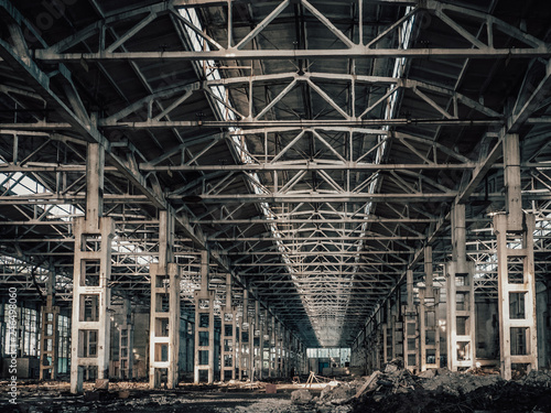 Large hall of abandoned and ruined factory or industrial warehouse inside with perspective