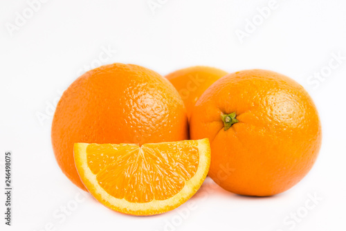 Three fresh juicy oranges and one slice lobule isolated on white background. Close photo