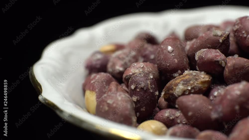 Raw unpeeled peanuts fried with salt. Rotation. Snack closeup. Peanuts in a bowl. Selective focus. black background. Studio shot. Healthy food concept. Raw unpeeled peanuts fried with salt. Rotation. Snack closeup. Peanuts in a bowl. Selective focus. black background. Studio shot. Healthy food concept.