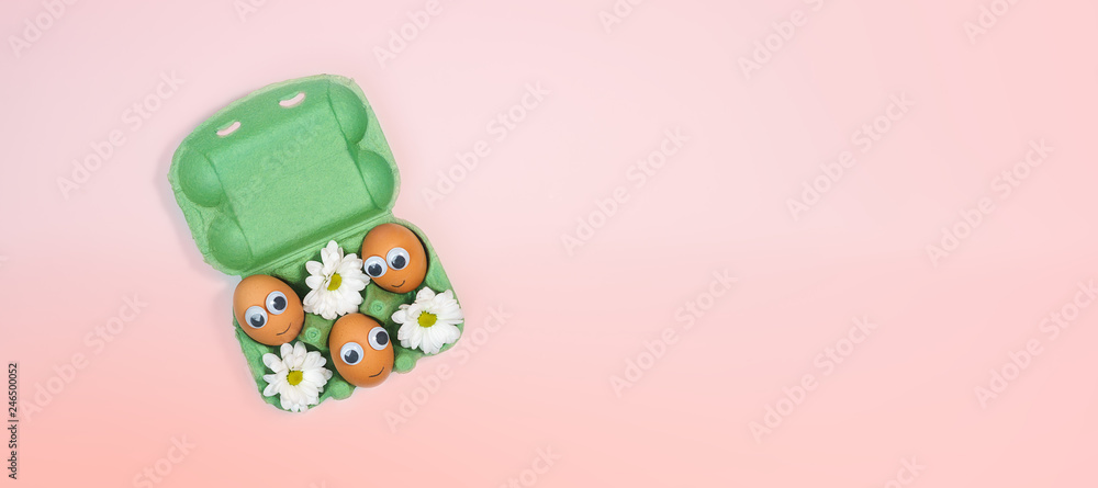 Top view to brown chicken eggs with eyes and smile in green box carton, flowers on living coral color background and red bow. Spring and Easter holiday concept with copy space. Flat lay, close up. Top view to brown chicken eggs with eyes and smile in green box carton, flowers on living coral color background and red bow. Spring and Easter holiday concept with copy space. Flat lay, close up.