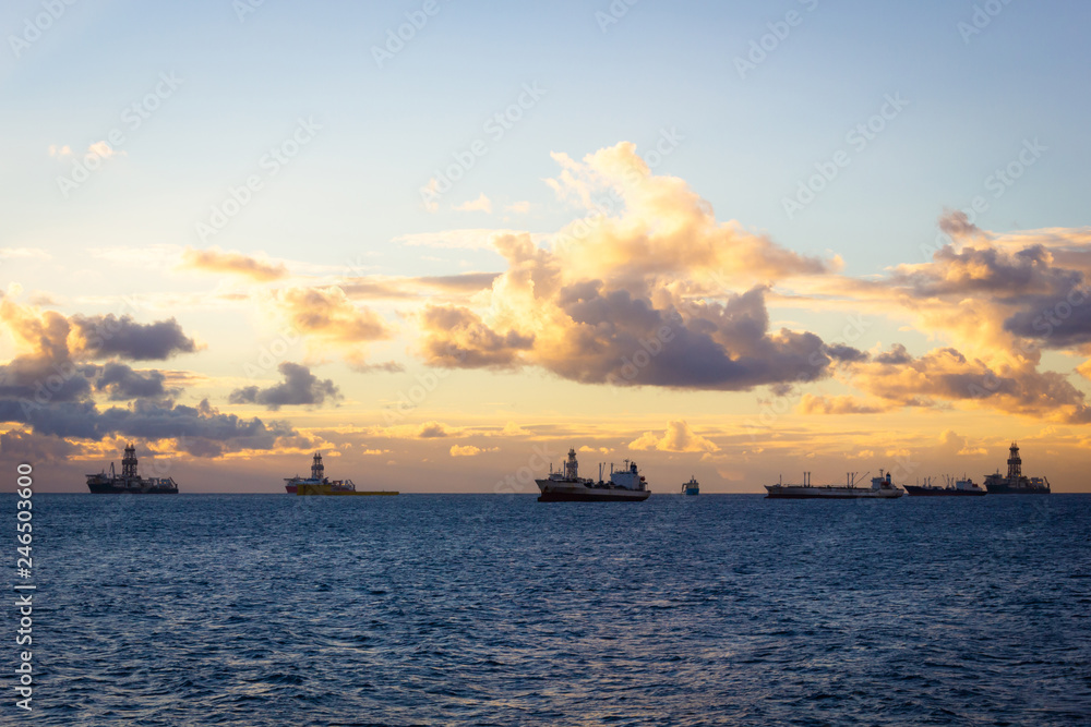 Offshore oil rig, platforms and big ships at sunrise in Las Palmas, Spain. Fossil fuel, climate change, air pollution, black gold concepts