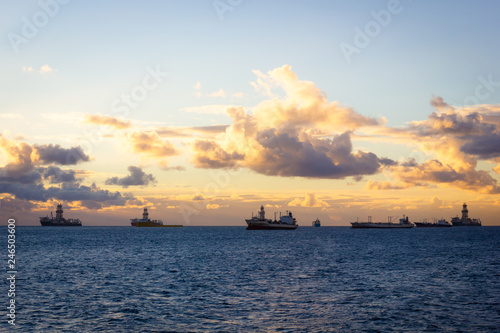 Offshore oil rig, platforms and big ships at sunrise in Las Palmas, Spain. Fossil fuel, climate change, air pollution, black gold concepts