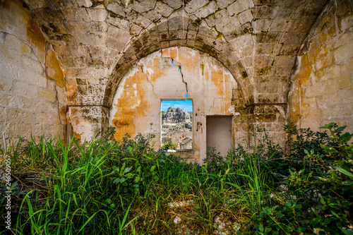 View through a window in a medieval, cracked stone wall of the ancient Madonna de Idris rock church and the Sassi of Matera, Italy, in the Basilicata region.