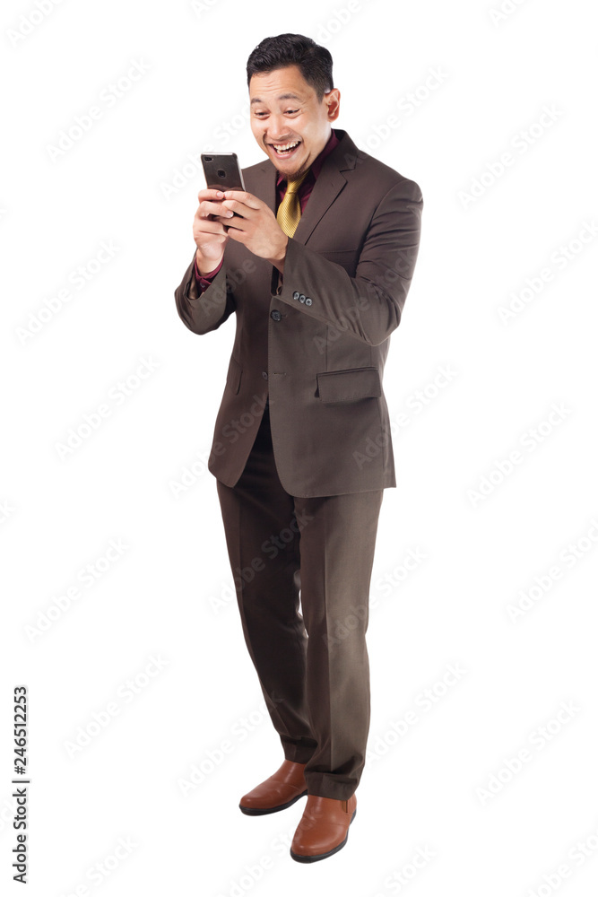 Attractive young businessman reading message on his phone, happy smiling Attractive young businessman reading message on his phone, happy smiling