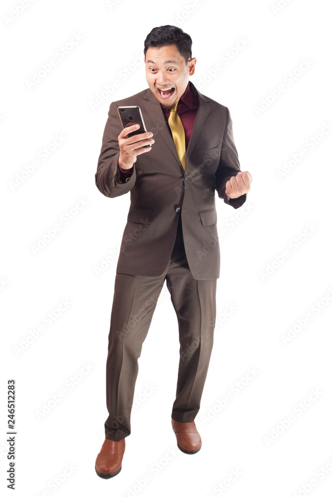 Attractive young businessman receive good news on his phone, happy winning gesture Attractive young businessman receive good news on his phone, happy winning gesture