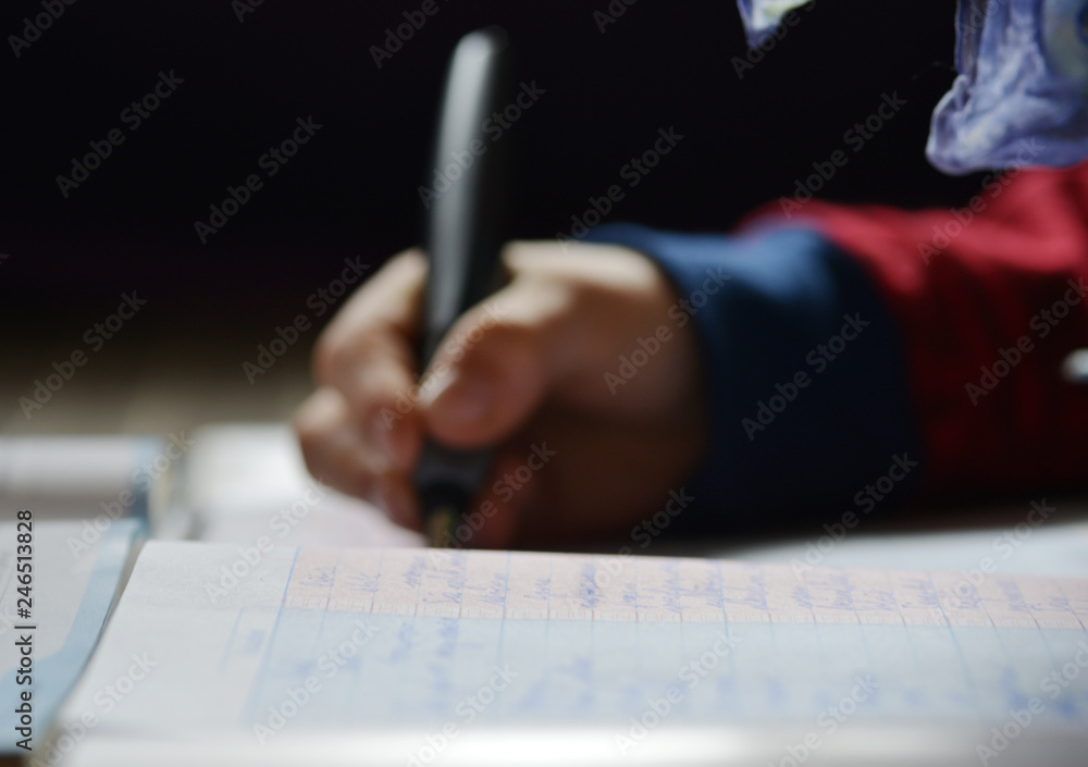 School handwriting a lesson into a notebook with a ink pen School handwriting a lesson into a notebook with a ink pen