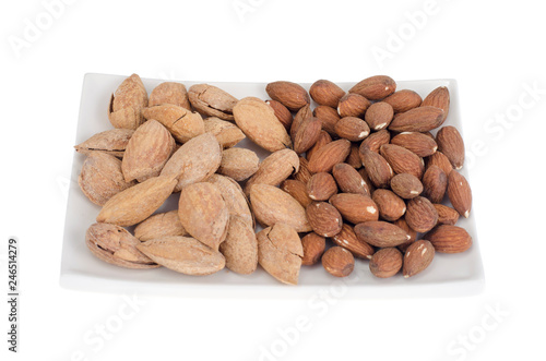 Dried peeled and unpeeled whole almonds on white plate