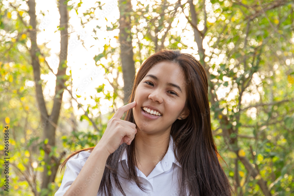 beautiful asian woman with hand on cheek with tree and sunlight in background. beautiful asian woman with hand on cheek with tree and sunlight in background.