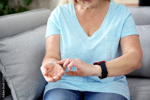 Mature woman checking pulse with fingers at home, closeup © New Africa