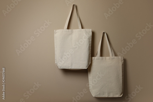 Eco tote bags hanging on color wall. Space for design