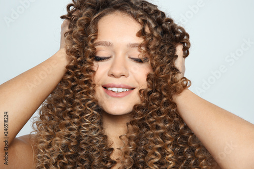Portrait of beautiful young woman with shiny wavy hair on color background, closeup