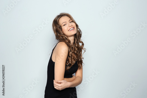 Portrait of beautiful young woman with shiny wavy hair on color background