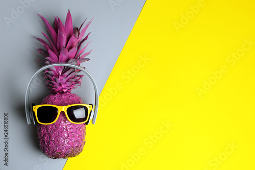 Pineapple with headphones and sunglasses on color background, top view with space for text
