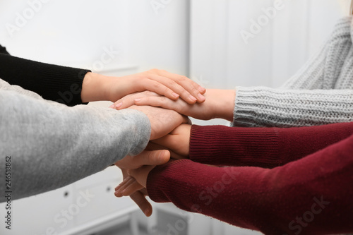 Young people putting their hands together on blurred background, closeup