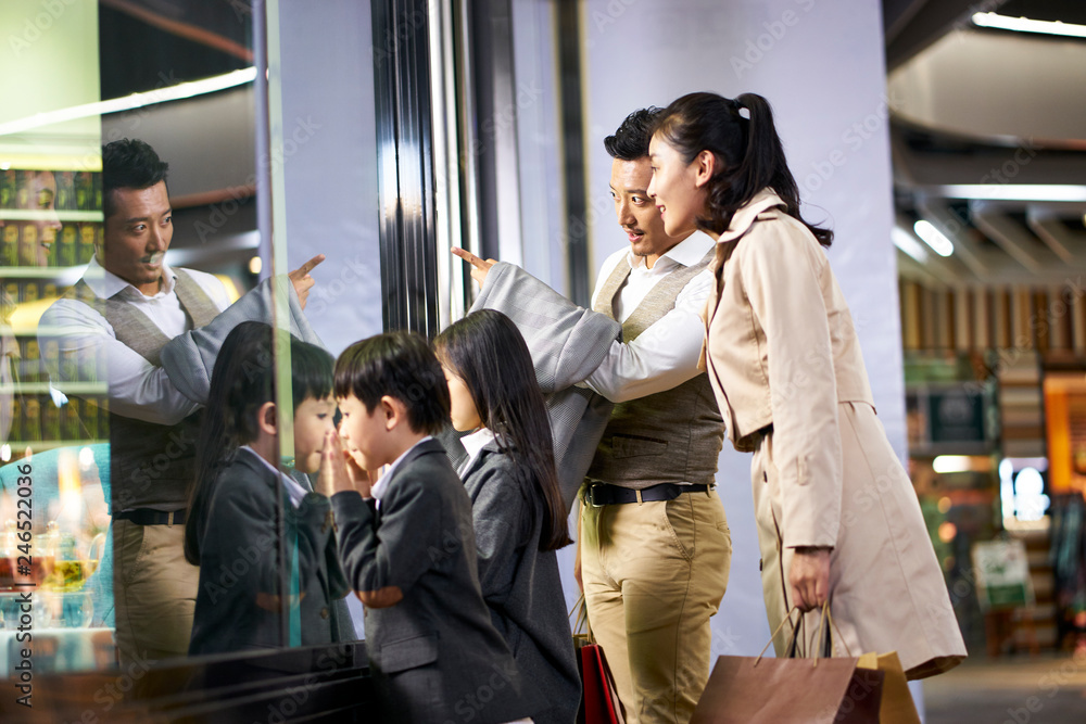 Obraz premium asian family looking into shop window