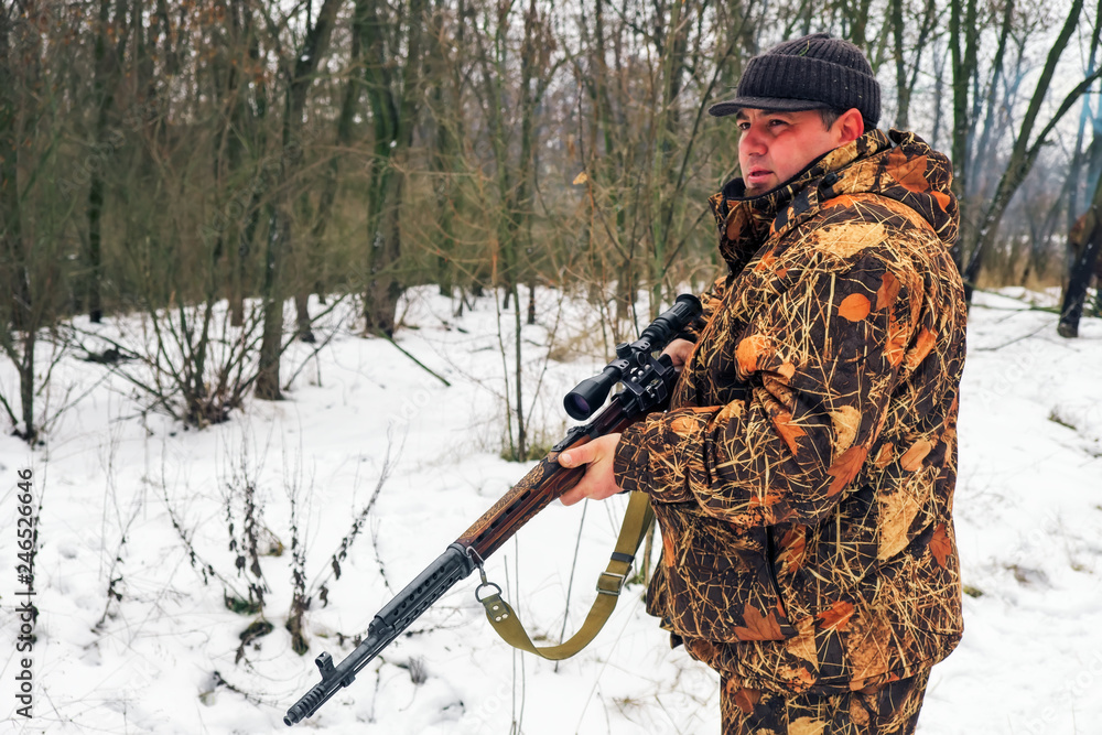 Fototapeta premium Winter hunting. Hunter moving With rifle and Looking For Prey.