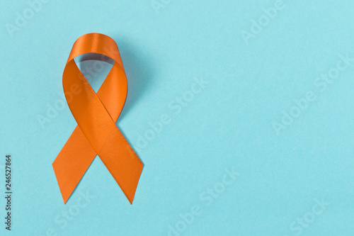 Orange ribbon on blue background . Healthcare and medicine concept. Multiple Sclerosis awareness. Leukemia awareness. Empty text space.