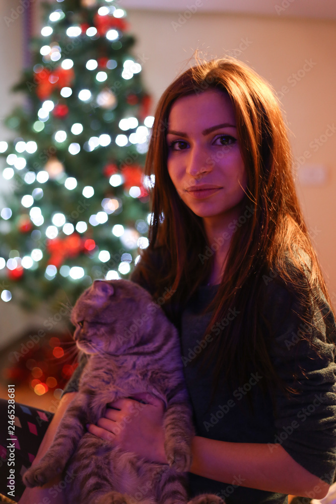 Portrait of young woman with can on hands and Christmas tree background 