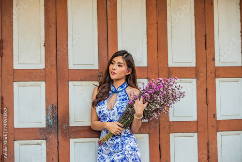 Asian girl in floral print dress standing in front door.