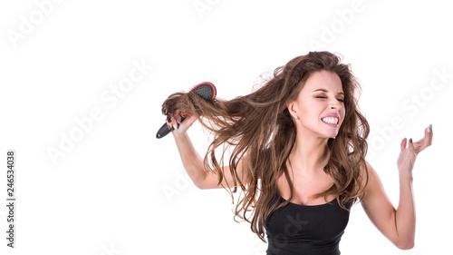 cute girl pulls out a comb from tangled hair and screams into the camera on a white background. Hair health concept