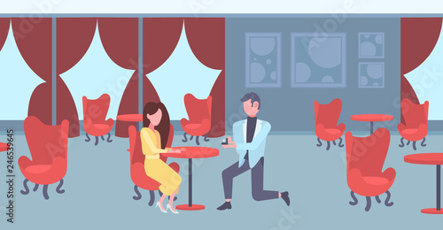 man kneeling holding engagement ring proposing to woman marry him happy valentines day concept couple in love marriage offer modern restaurant interior horizontal