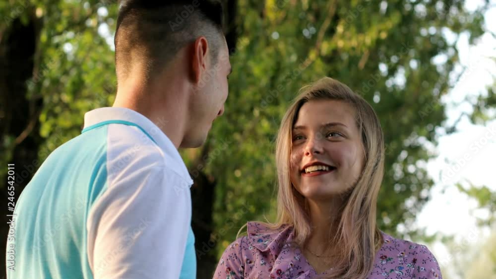 A young couple, the family spends the weekend in the park. They are pleasantly talking, happy together. A young couple, the family spends the weekend in the park. They are pleasantly talking, happy together.