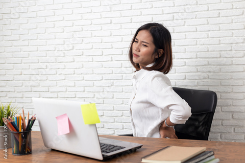 Business woman suffering from back pain in office home photo