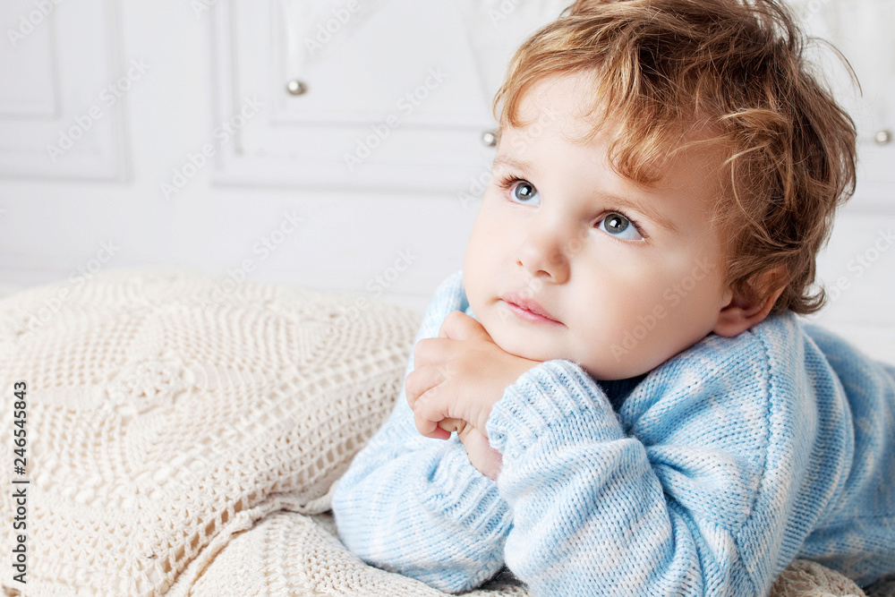 Portrait of happy adorable baby boy on the bed in his room. Thoughtful look up. Copy space Portrait of happy adorable baby boy on the bed in his room. Thoughtful look up. Copy space
