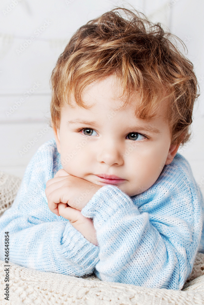 Portrait of happy adorable baby boy on the bed in his room. Thoughtful look.