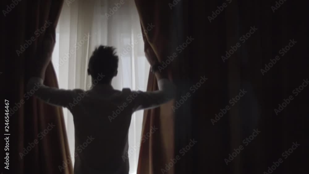 Man Open Big Window Curtains.Man In Dark Room Opens Curtains Slow Motion.Man Unveil Curtains And Admire Garden View From Window In Slow Motion.Man Looking At Window Slow Motion.Guy Stay Against Window