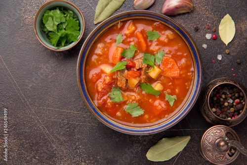 Thick tomato soup with meat, cereals and vegetables. Traditional Oriental cuisine, spicy stew with beef or lamb, rice and spices. Food on dark background