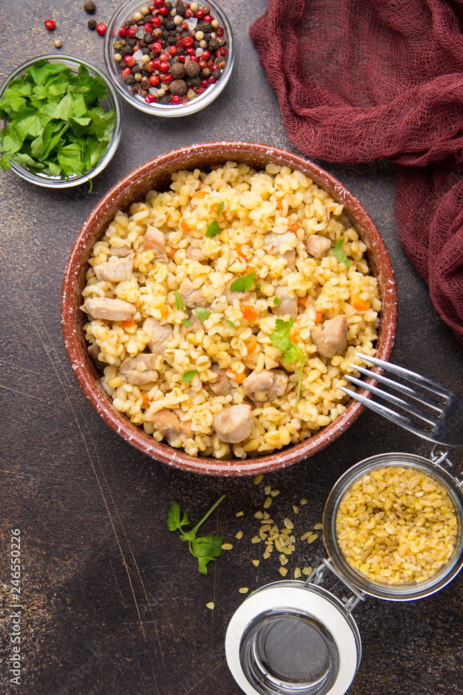 Bulgur with turkey, pork or beef. Eastern dish of rice, delicious traditional food. Stewed meat with grits. Pilaf on dark background Bulgur with turkey, pork or beef. Eastern dish of rice, delicious traditional food. Stewed meat with grits. Pilaf on dark background