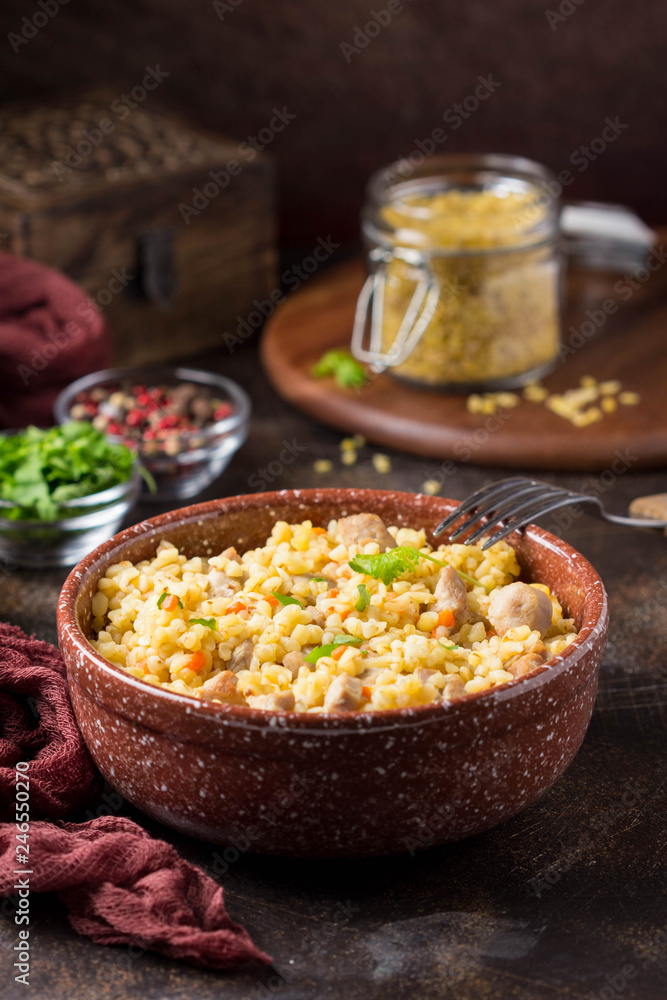 Bulgur with turkey, pork or beef. Eastern dish of rice, tasty traditional food. Stewed meat with grits. Pilaf on dark background Bulgur with turkey, pork or beef. Eastern dish of rice, tasty traditional food. Stewed meat with grits. Pilaf on dark background