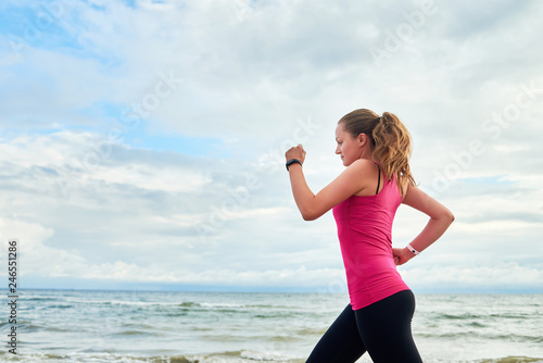 Athletic woman running on sea beach  copy space. Female runner working out at summer morning  side view. Healthy lifestyle concept