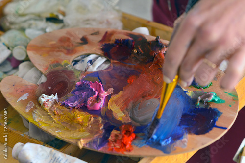 Close up of woman's hand mix paints with brush in pallete in art-class