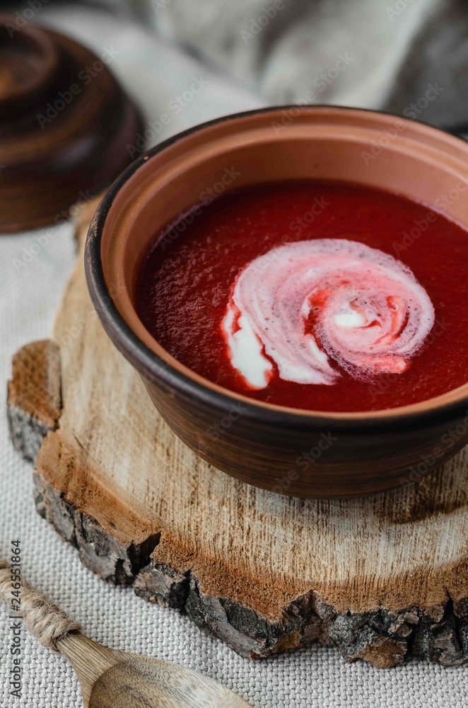 Ukrainian borscht red soup in bowl and wooden spoon. Rustic style. Close up