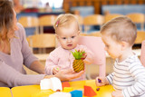 Babies learn playing toys with teacher in nursery