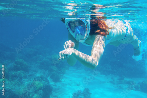 Woman in bikini show time underwater. Snorkeling in tropical sea coral reef. Young girl in full-face snorkeling mask