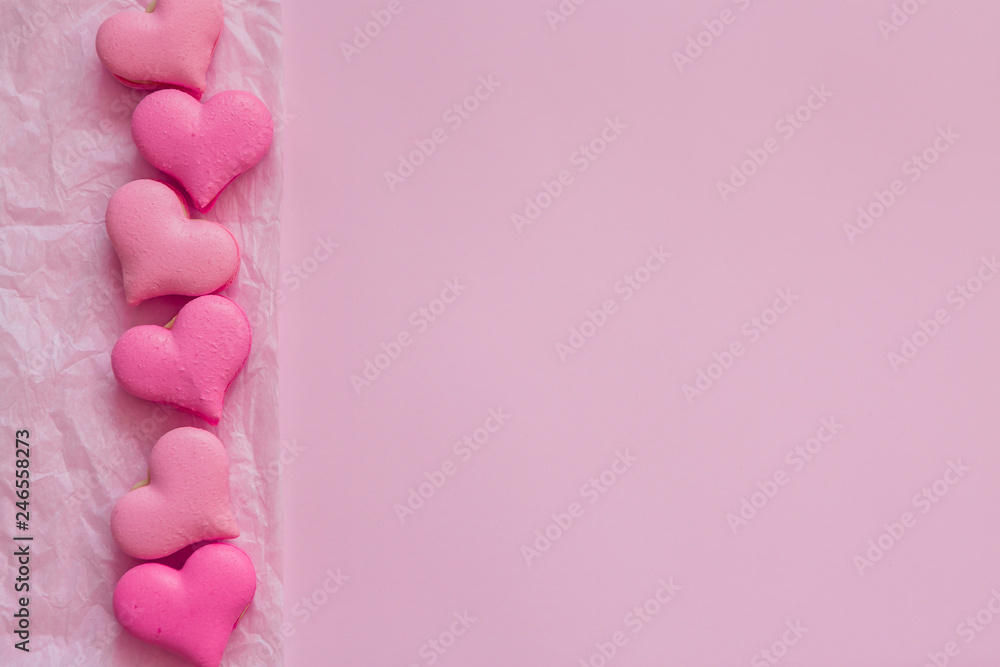 macaroons in the form of hearts on pink backdrop of.heart-shaped macaroons on pink background.Macaroons Heart.Valentine's Day.Pink gift tied with rosy ribbon and macaron macaroon cookie on pink heart 