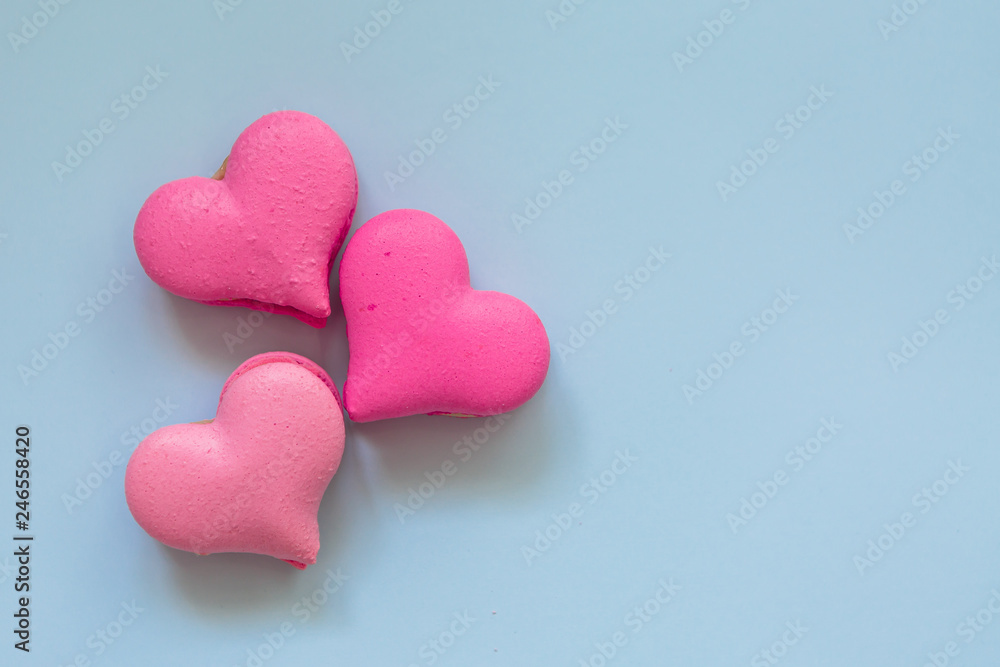 heart-shaped macaroons on blue background.Valentine's Day. Pink gift tied with rosy ribbon and macaron macaroon cookie on pink heart background top view. Valentines Day, 8 March, Womens Day, Birthday heart-shaped macaroons on blue background.Valentine's Day. Pink gift tied with rosy ribbon and macaron macaroon cookie on pink heart background top view. Valentines Day, 8 March, Womens Day, Birthday