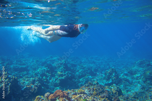 Young woman snorkeling underwater photo. Snorkel in coral reef of tropical sea. Young girl in fullface snorkeling mask.