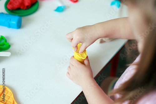 Child playing with colorful clay molding different shapes - closeup on hands, copy space