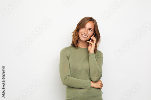 portrait of young smiling woman with mobile phone looking left