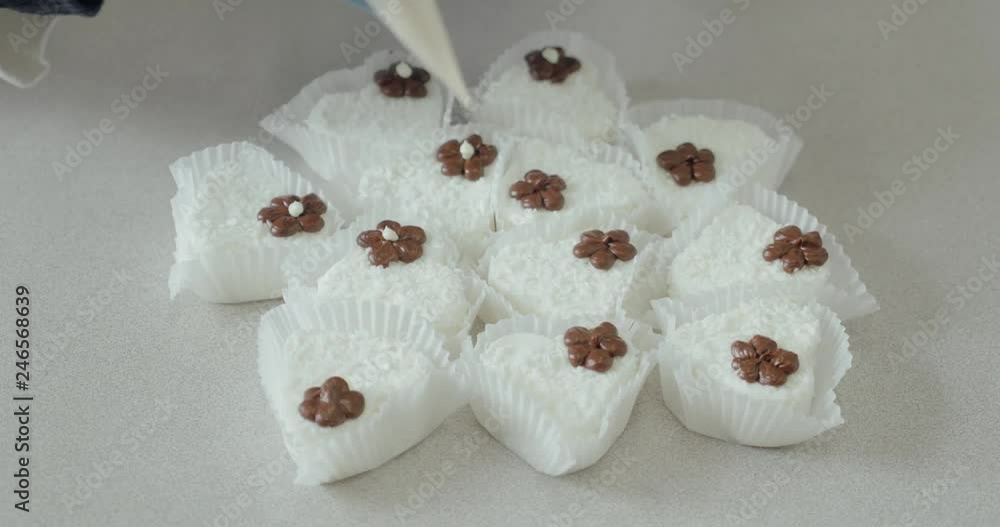 Chocolate factory, confectioner decorates candies with coconut flakes with cream, handwork. Chocolate factory, confectioner decorates candies with coconut flakes with cream, handwork.